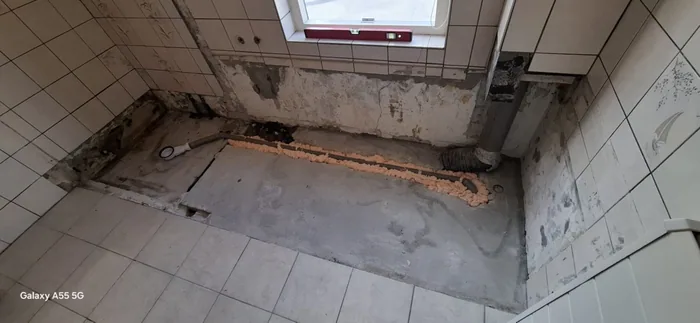 Plek van het oude bad gesloopt, nieuwe afvoer ingefreesd in de vloer onder het raam