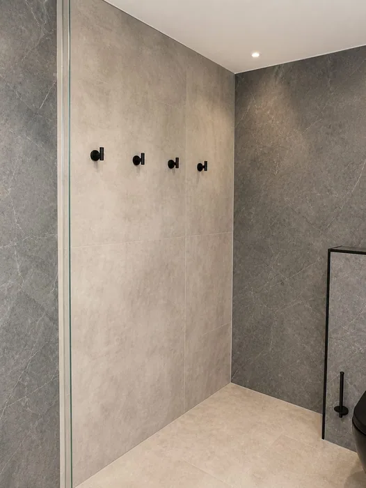 Grijze wand met zwarte haakjes en een strakke betonlook wand en vloer