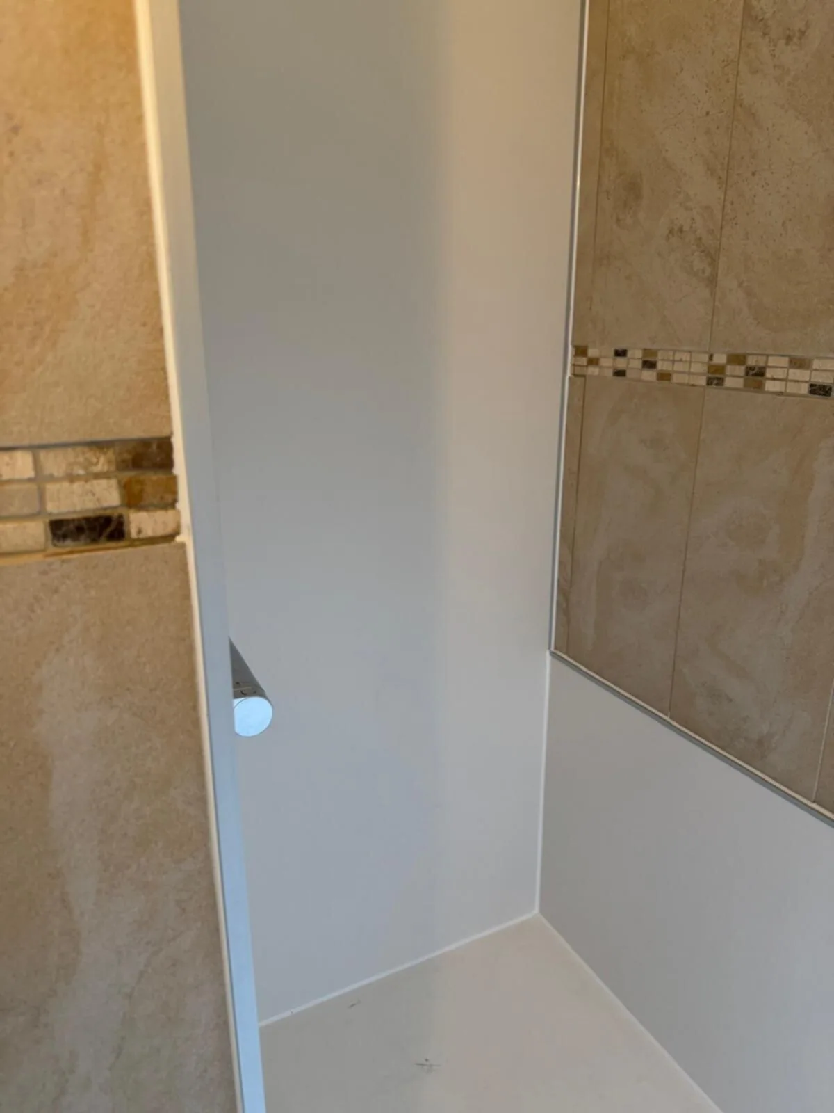 Douchenis met nieuwe witte wandpanelen en douchevloer, met de bestaande beige tegels eromheen