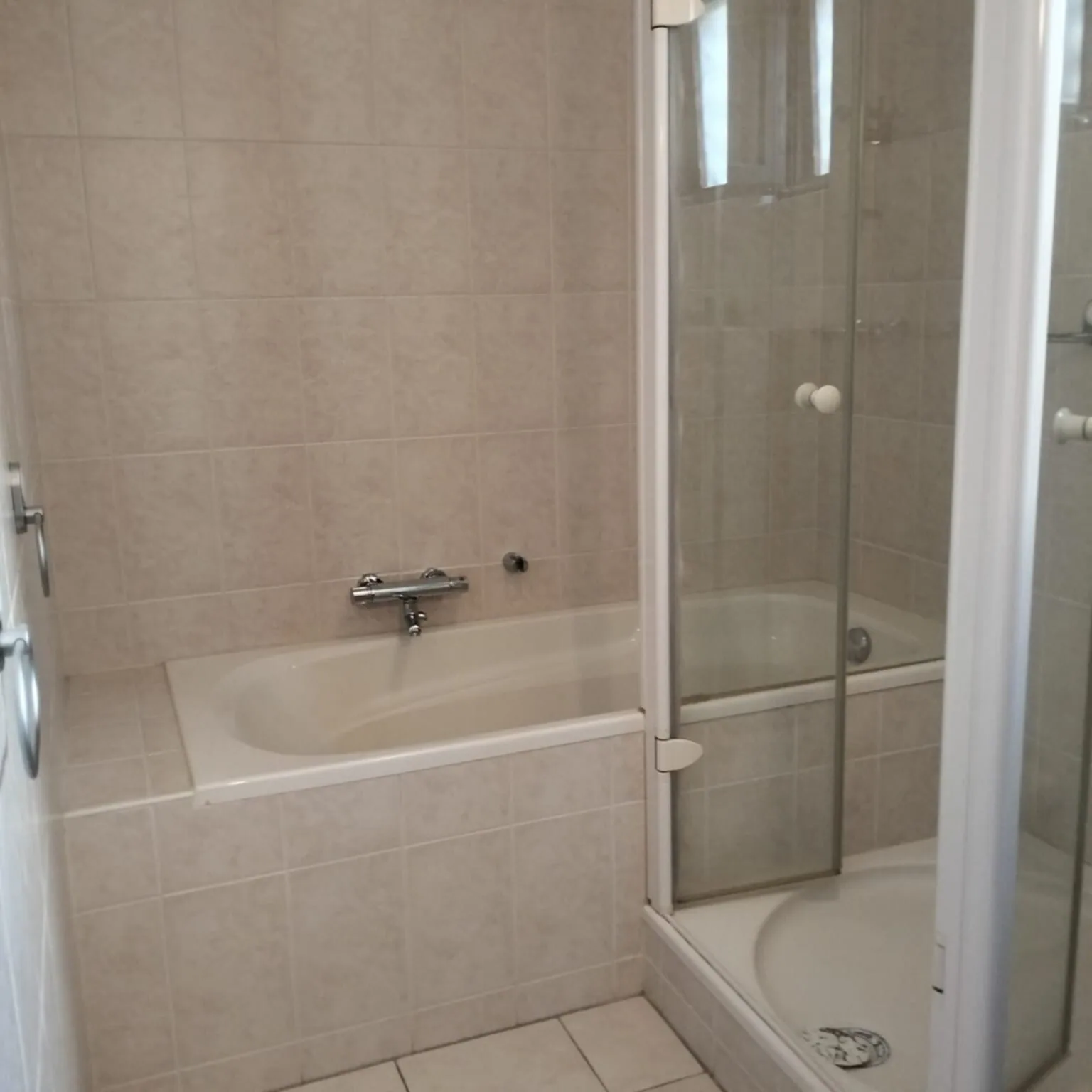 Oude situatie: badkamer met ligbad, douchecabine met kwartronde bak en beige tegels