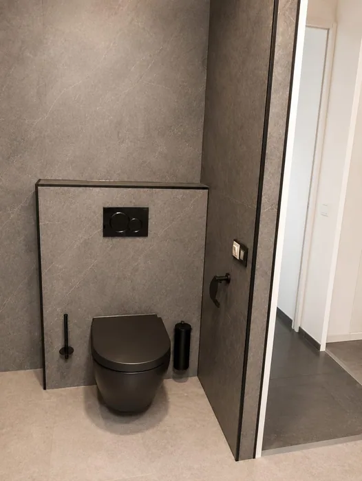 Zwart hangtoilet tegen een grijze voorzetwand met zwart bedieningspaneel