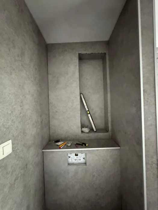 Voorzetwand met nis voor het hangtoilet, bekleed met grijze stenenlook panelen